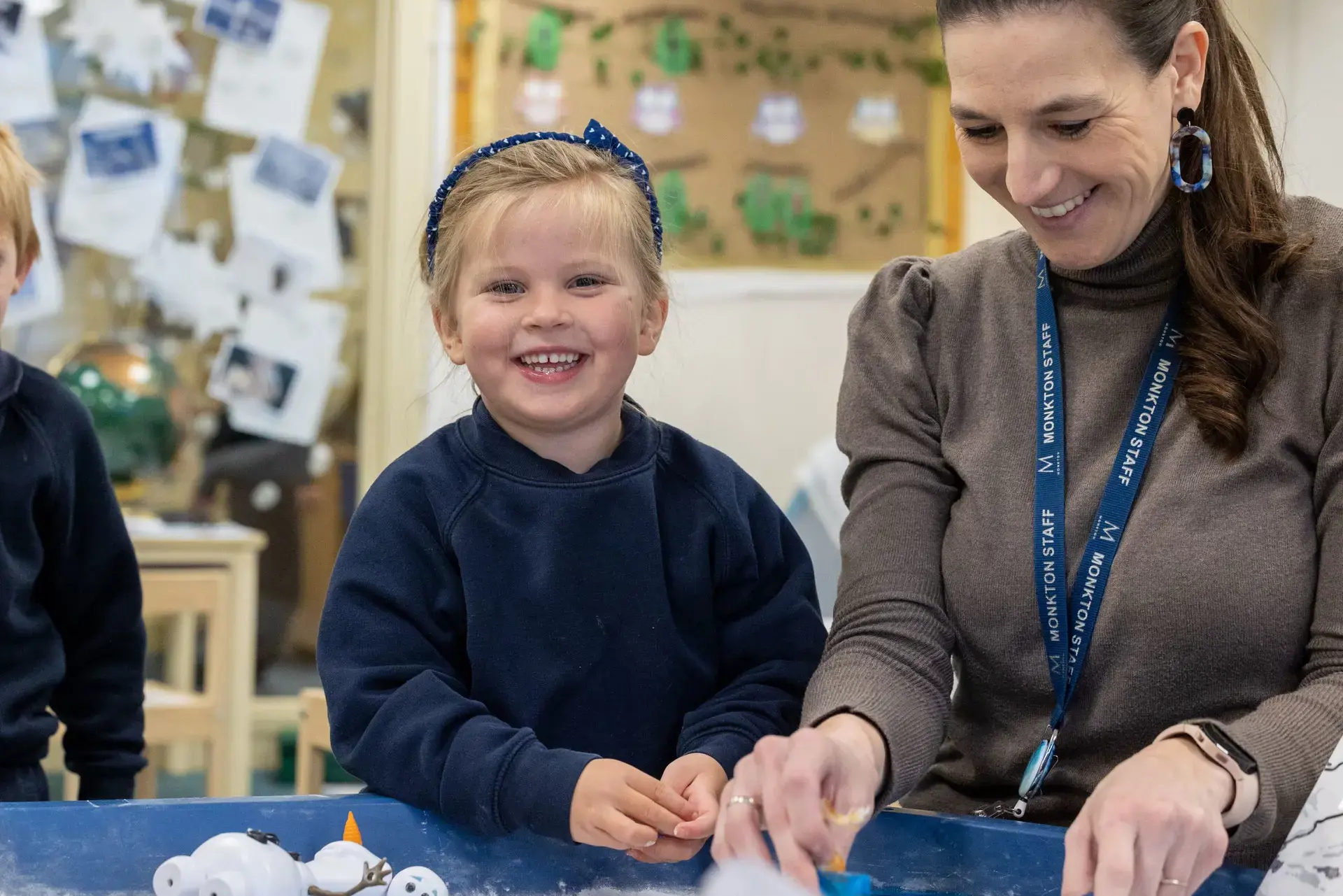 teacher helping nursery pupil